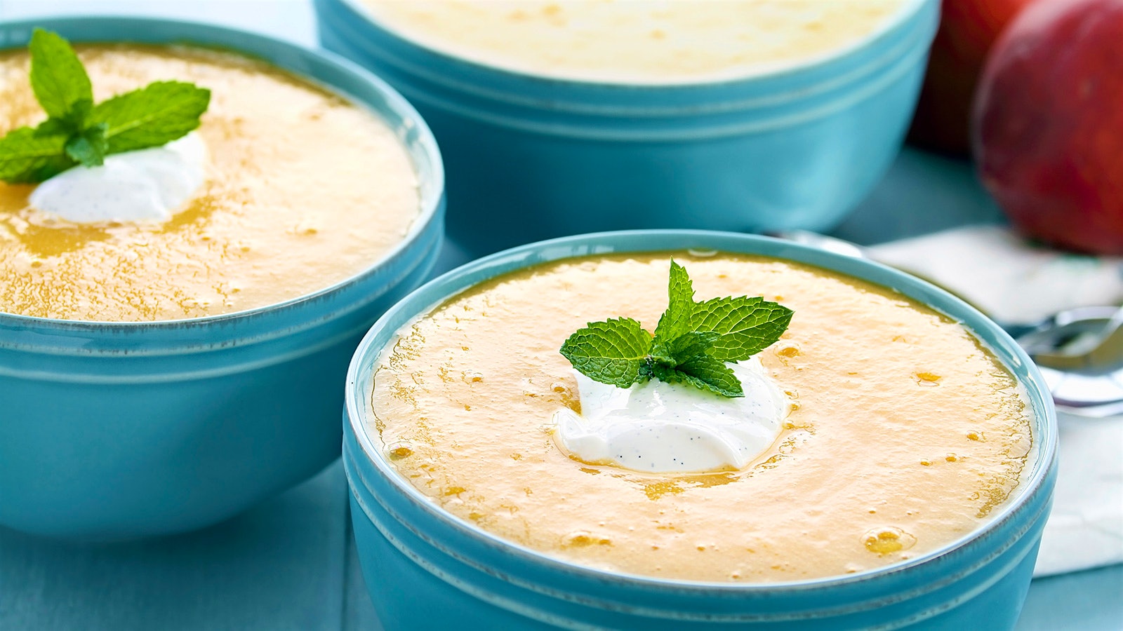  Bowls of chilled peach soup topped with a dollop of cream and mint leaves 